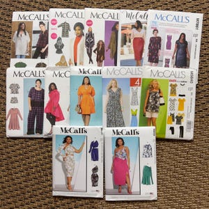 May include: A collection of twelve McCall's sewing pattern envelopes arranged in three rows. Each envelope features printed branding, model photographs displaying various garments like dresses, skirts, and tops, along with technical illustrations of the designs.