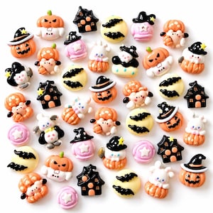 May include: A collection of small, colorful resin cabochons featuring Halloween themes. The assortment includes orange jack-o'-lanterns, black haunted houses, pale yellow moons with black bats, white ghosts in pumpkins, and pink circles with stars.