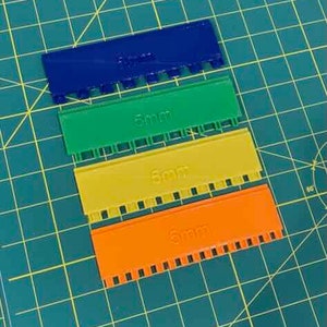 May include: Four plastic rulers with different measurements: 3mm, 5mm, 6mm, and 8mm. The rulers are blue, green, yellow, and orange.