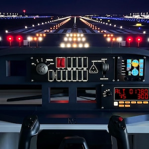 May include: A detailed model airplane cockpit with illuminated gauges, switches, and displays. The dark blue control panel features a digital altimeter, a small screen, and two black control sticks. The background shows a lit-up runway at night.