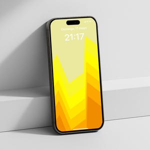 May include: A black smartphone with a yellow and orange geometric design on the screen, leaning against a white surface. The screen displays the date and time. The phone has a sleek, modern design.