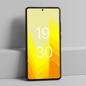 May include: A black smartphone with a yellow and orange geometric design on the screen, displaying the time 19:30 in white. The phone is leaning against a gray surface.