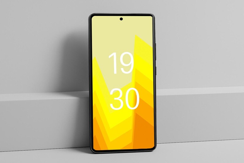 May include: A black smartphone with a yellow and orange geometric design on the screen, displaying the time 19:30 in white. The phone is leaning against a gray surface.