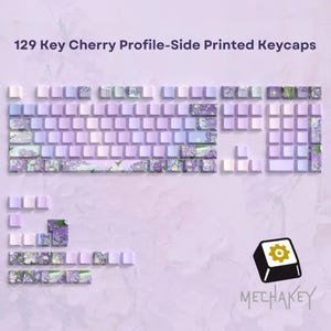 May include: A set of 129 Cherry Profile side-printed keycaps in shades of purple, lavender, and white. Some keycaps feature floral designs. The image includes a logo with a gear icon and the word "MECHAKEY".