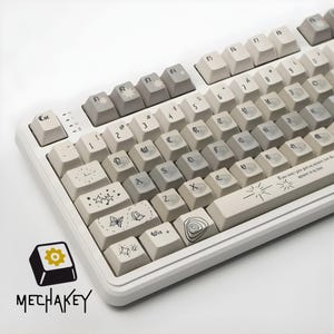 May include: A white mechanical keyboard with custom keycaps. The keycaps are a mix of off-white and gray, featuring various line art designs such as stars, butterflies, and swirls. The keyboard has the text "MECHAKEY" in the lower left corner.