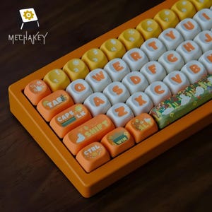 May include: A close-up of a mechanical keyboard with orange, white, and yellow keycaps. The keycaps display letters, numbers, and symbols in orange and white. The keyboard has a bright orange frame. The brand name "MECHAKEY" is visible.