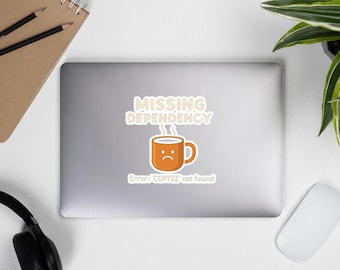 May include: A sticker with the text "MISSING DEPENDENCY" above a cartoon coffee mug with a sad face. Below the mug, the text reads "Error: COFFEE not found". The mug is orange with a white outline, and the text is in a sans-serif font.