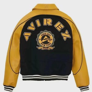 K&ouml;nnte beinhalten: Schwarz-gelbe Collegejacke mit dem Wort "AVIREX" auf dem R&uuml;cken. Die Jacke hat ein klassisches Design mit schwarzem K&ouml;rper, gelben &Auml;rmeln und einem wei&szlig;-schwarz gestreiften Saum. Auf der R&uuml;ckseite befindet sich ein Emblem "Since 1975 New York Classic".