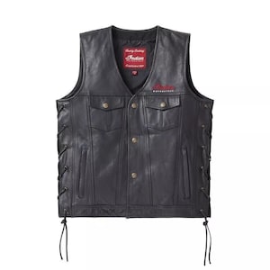 May include: Black leather vest with a V-neck, two chest pockets, and two lower pockets. The vest has button closures and side laces. The Indian Motorcycle logo is embroidered in red on the chest. A red tag with the Indian Motorcycle logo is sewn inside.