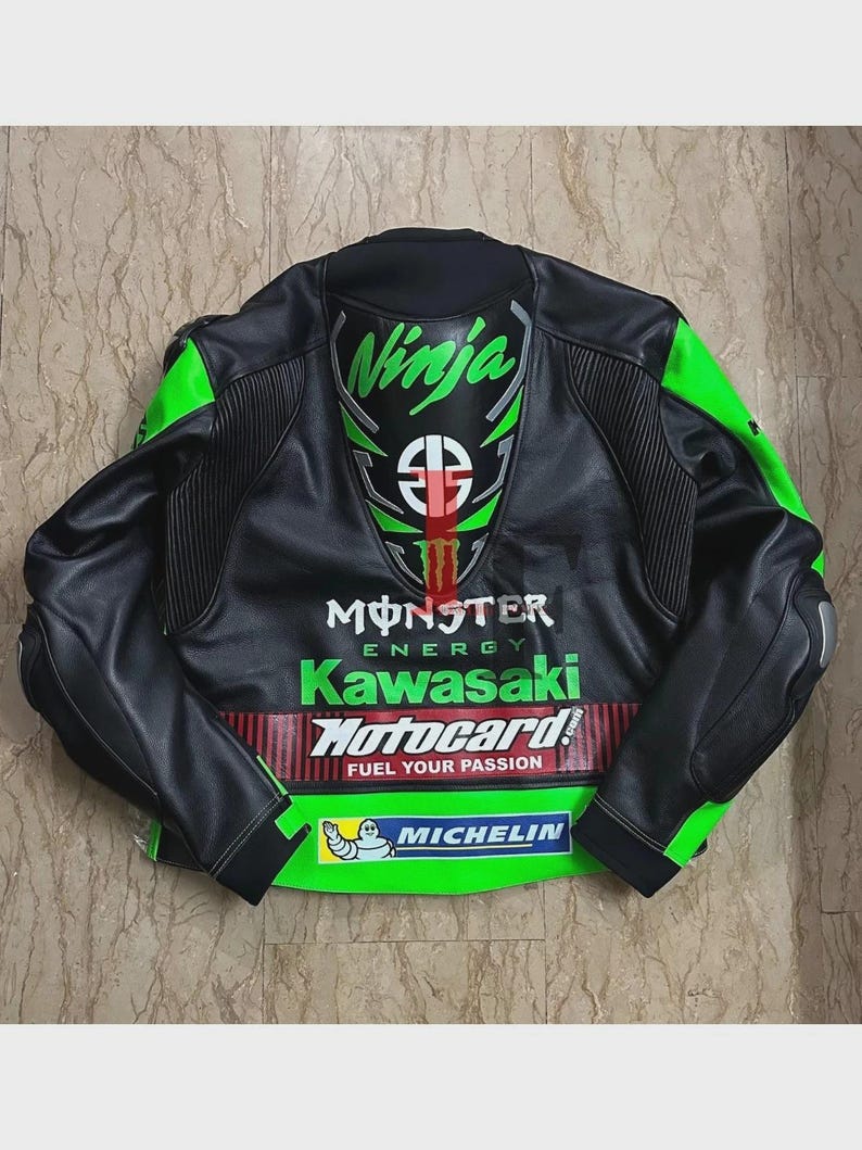 May include: Black and green motorcycle jacket with "Ninja" and "Monster Energy Kawasaki" logos. The jacket features a "Motocard" logo and "Fuel Your Passion" text, along with a Michelin logo. The jacket has green accents on the shoulders and sleeves.