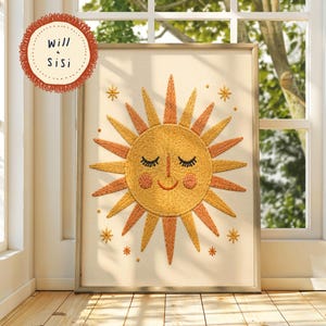 Könnte beinhalten: Gestickte Kunst mit einer lächelnden Sonne mit geschlossenen Augen, die orange und gelbe Strahlen ausstrahlt. Die Sonne ist von kleinen Sternakzenten umgeben. Das Kunstwerk ist in einem hellfarbigen Holzrahmen gerahmt. Der Text "Will & Sisi" befindet sich in einem kreisförmigen Design.