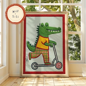 May include: Embroidered artwork of a green alligator on a scooter, wearing a yellow top and plaid trousers. The artwork is framed in wood with a red border. The text "Will & Sisi" is included. The artwork is displayed in a window.