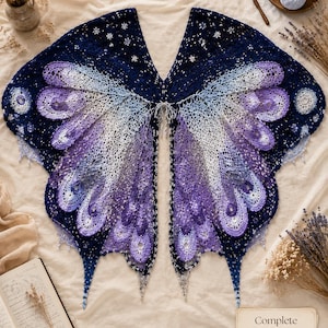 May include: A crochet shawl designed to resemble butterfly wings, featuring a gradient of dark navy blue, light blue, and purple yarn. The intricate lace pattern includes small star-shaped motifs and scalloped edges, with a card labeled Complete Pattern Preview.