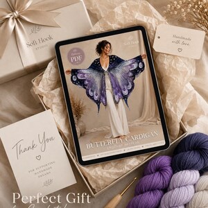 May include: A digital tablet displaying a crochet pattern for a butterfly cardigan, accompanied by three skeins of yarn in shades of purple, a wooden crochet hook, a gift box with a ribbon, and a thank you card from Soft Hook Studio.