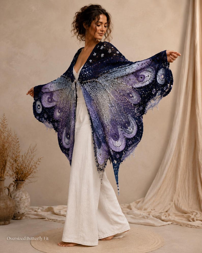 May include: An oversized crochet shawl featuring a butterfly wing pattern in shades of deep navy, violet, and light lavender. The intricate openwork design includes circular motifs and star-like accents. The text Oversized Butterfly Fit is visible.