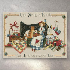 Può includere: Opera d'arte a punto croce con una macchina da cucire vintage, una donna in abito blu e un gatto. L'opera d'arte include il testo "Love Sews a Bond that Time can never Tear". La scena è piena di articoli da cucito e una trapunta.