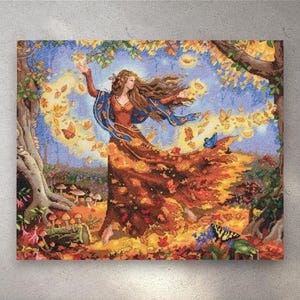 May include: Cross-stitch artwork depicting a woman in a flowing orange dress, surrounded by autumn leaves and butterflies. The woman has long brown hair and is reaching out. The background features trees, mushrooms, and a blue sky.