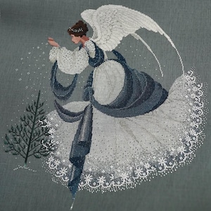 Puede incluir: Un diseño de punto de cruz de un ángel con un vestido blanco y azul fluido con grandes alas blancas. El ángel está rociando chispas cerca de un pequeño árbol de hoja perenne. El fondo es gris apagado.