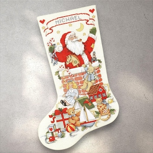 May include: A Christmas stocking featuring a Santa Claus design, chimney, and toys. The name "MICHAEL" is embroidered at the top. The stocking has a red, white, and green colour scheme, with various festive elements.