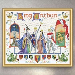 Op de afbeelding: Een ingelijste kruissteekafbeelding van Koning Arthur en zijn hof. Het kunstwerk toont Koning Arthur, een tovenaar en andere figuren in middeleeuwse kleding. De titel "King Arthur" staat bovenaan. De afbeelding bevat een schip, een kasteel en heraldische symbolen.