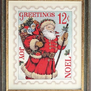 May include: Framed cross-stitch art featuring Santa Claus carrying a basket of toys. The image is designed to look like a postage stamp with the words "GREETINGS," "JOY," and "NOEL." Santa is wearing a red suit with white trim and holding a staff.