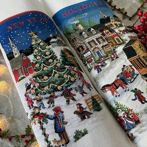 May include: Two white fabric panels with embroidered winter holiday scenes. One panel features a Christmas tree and the words "NEW YEAR" in red letters. The other panel shows a village scene and the word "HOLIDAYS" in blue letters.