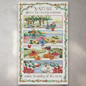 May include: A framed cross-stitch artwork with the text "NATURE gives to every season some beauty of its own." The artwork depicts four seasonal scenes: spring, summer, autumn, and winter, with trees, flowers, and landscapes. The frame has a vine border.