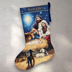 May include: Blue Christmas stocking with a nativity scene. The stocking features the text "Christopher" in gold lettering. The scene depicts Mary, Joseph, and baby Jesus, with animals and a star in the background.