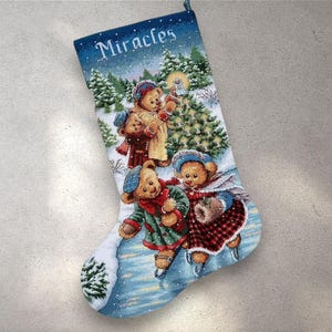 Könnte beinhalten: Weihnachtsstrumpf mit einer Winterszene mit Eis laufenden Teddybären, die eine Laterne halten. Der Strumpf ist blau mit dem Wort "Miracles" oben. Die Bären tragen Winterkleidung in Rot, Grün und Beige.