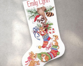 May include: White Christmas stocking with embroidered woodland creatures and the name "Emily Lynn" in red. Features a raccoon in a Santa hat, a fox, a bunny, and a mouse, all with festive details. Includes a candy cane and decorative bows.