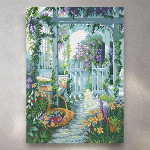 Puede incluir: Un patrón de punto de cruz que representa una escena de jardín con un cenador de madera azul claro cubierto de glicinias moradas. Un camino de piedra atraviesa la estructura, flanqueado por flores amarillas y moradas y una cesta tejida con flores.