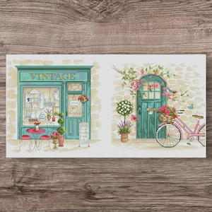 Könnte beinhalten: Kreuzstichmuster mit einem Vintage-Laden und einem Fahrrad mit einem Blumenkorb. Der Laden hat eine türkisfarbene Fassade mit dem Wort "VINTAGE" über der Tür. Ein rosa Fahrrad steht neben einer türkisfarbenen Tür.