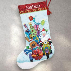 May include: A light blue Christmas stocking with a red cuff embroidered with the name "Joshua". The stocking features a Santa Claus riding a motorcycle, a Christmas tree, and wrapped gifts. The stocking is decorated with snowflakes.