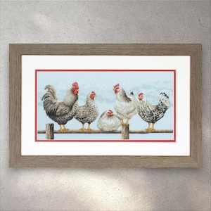 Pode incluir: Uma bordada em ponto cruz emoldurada retratando seis galinhas empoleiradas em uma cerca de madeira. As galinhas estão em várias tonalidades de cinza, branco e preto, com cristas vermelhas. O fundo é um céu azul claro. A moldura é de cor castanho claro.