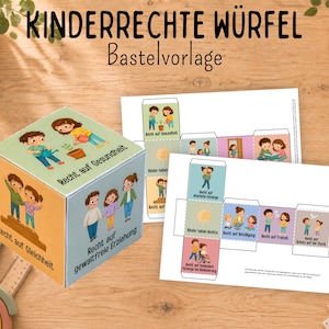 Könnte beinhalten: Ein Papierwürfel zum Basteln und zwei Druckvorlagen mit Illustrationen von Kindern und deutschem Text. Der Würfel zeigt Szenen mit den Aufschriften Recht auf Gesundheit, Recht auf Gleichheit und Recht auf gewaltfreie Erziehung.