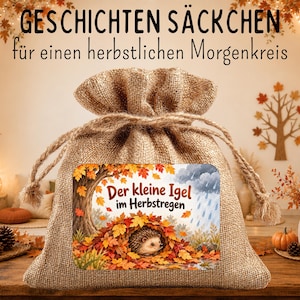 May include: A tan burlap drawstring pouch featuring a rectangular label with an illustration of a hedgehog nestled in autumn leaves under a tree. The text on the label reads 'Der kleine Igel im Herbstregen' and the top text reads 'GESCHICHTEN SÄCKCHEN für einen herbstlichen Morgenkreis'.