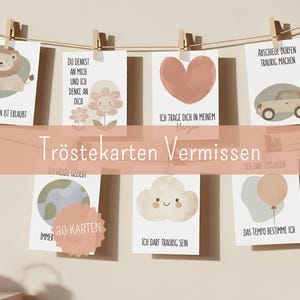 May include: A display of illustrated cards with various designs, including a lion, flowers, a heart, and a car. The cards are held by wooden clips on a string. Text on the cards includes phrases like "Missing is allowed" and "I carry you in my heart."