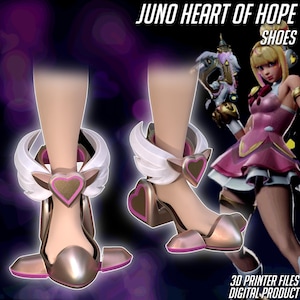 Op de afbeelding: Metallic goudkleurige en roze schoenen met hart- en vleugelaccenten. De schoenen hebben een hoge hak en een futuristisch ontwerp. De tekst "JUNO HEART OF HOPE SHOES" en "3D PRINTER FILES DIGITAL PRODUCT" is zichtbaar.