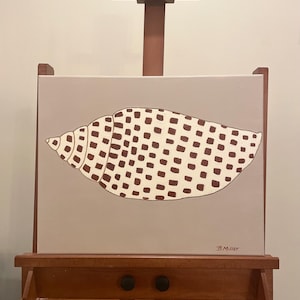 以下が含まれることがあります： 木製のイーゼルに飾られた、貝殻の絵画。貝殻はベージュ色で、茶色の四角い模様があります。キャンバスは薄茶色の背景です。アーティストのサイン「B. Miller」が見えます。