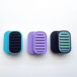 Puede incluir: Un juego de tres tazas de cerámica con un acabado mate moteado. Las tazas son en tonos crema, marrón claro y marrón oscuro. Cada taza tiene un diseño simple y minimalista y un asa redondeada.