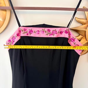 Puede incluir: Vestido negro con tirantes finos y una banda rosa en la parte superior. La banda rosa est&aacute; bordada con flores rosas y vides verdes. El vestido mide aproximadamente 35,5 cm en la parte superior.