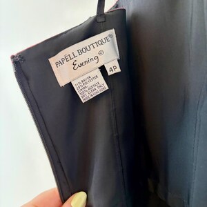 Puede incluir: Primer plano de un vestido de noche negro con cremallera y una etiqueta que dice "PAPELL BOUTIQUE Evening". La etiqueta tambi&eacute;n indica que el vestido es talla 4P y est&aacute; hecho de ray&oacute;n, poli&eacute;ster y acetato. El vestido est&aacute; hecho en Hong Kong.
