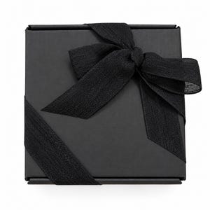 May include: A square black gift box featuring a matte finish, wrapped with a textured black ribbon tied into a decorative bow on the top surface. The ribbon extends diagonally across the box, creating a clean and uniform appearance.