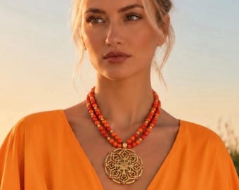 May include: A double-strand necklace featuring vibrant orange spherical beads interspersed with small gold-toned spacers. The necklace includes a large, circular gold-toned pendant with an intricate, symmetrical openwork filigree pattern.