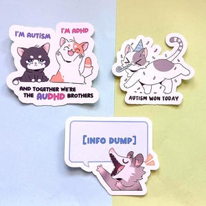 Può includere: Tre adesivi colorati con grafica a cartoni animati. Un adesivo presenta due gatti con il testo "I'M AUTISM" e "I'M ADHD" sopra di loro e "AND TOGETHER WE'RE THE AUDHD BROTHERS" sotto. Un altro adesivo mostra un gatto con un cappello da festa e il testo "AUTISM WON TODAY". Il terzo adesivo ha un opossum con il testo "[INFO DUMP]"