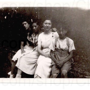 Fotografía de 1930: mujeres y un niño sentados afuera en una pared