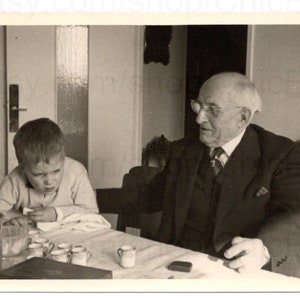 Fotografía francesa: un anciano sentado a la mesa con un niño