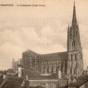 May include: Vintage sepia-toned postcard featuring Chartres Cathedral in France. The cathedral's tall spire dominates the skyline, with intricate architectural details visible. The postcard has text at the top, and is a historical travel souvenir.