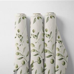 May include: Three rolls of fabric with a repeating olive branch pattern. The fabric is a light cream color, and the olive branches are green with black olives. The rolls are displayed vertically against a white background.