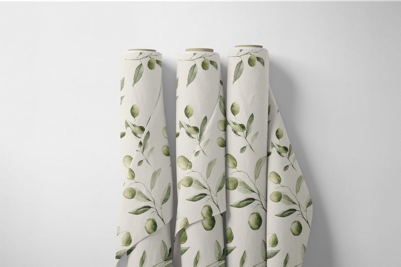 May include: Three rolls of fabric with a repeating olive branch pattern. The fabric is a light cream color, and the olive branches are green with black olives. The rolls are displayed vertically against a white background.